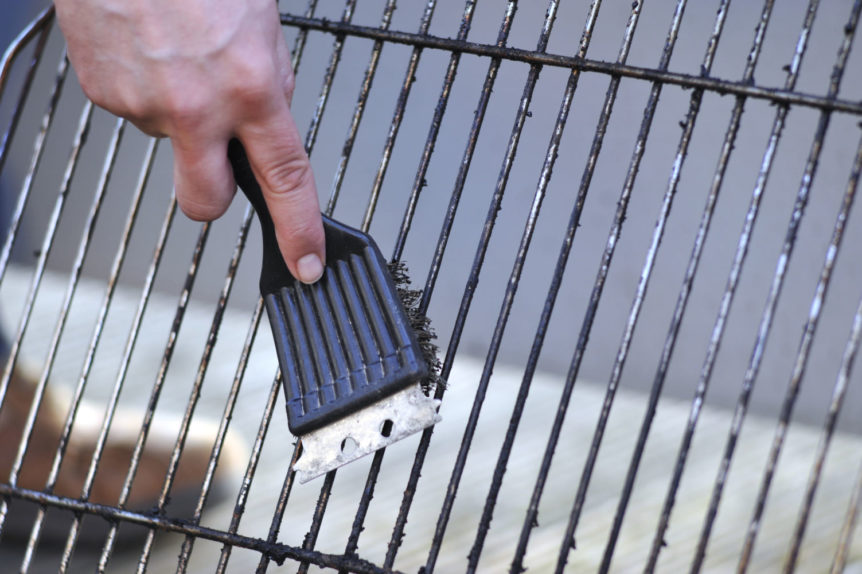 a person cleaning the grill with scrubber