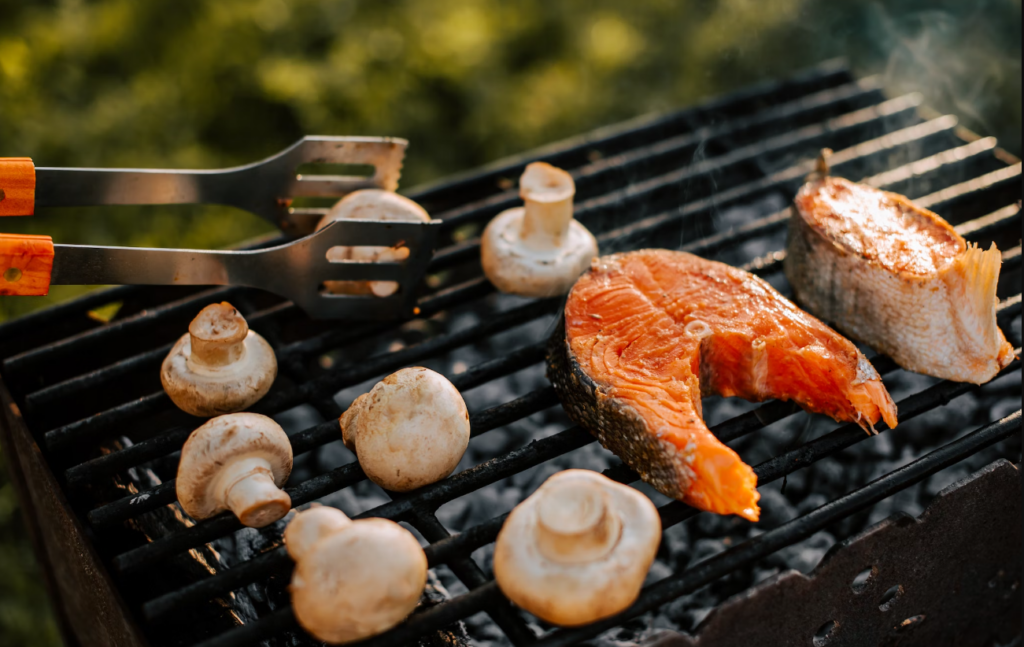 Someone grilling mushrooms with salmon